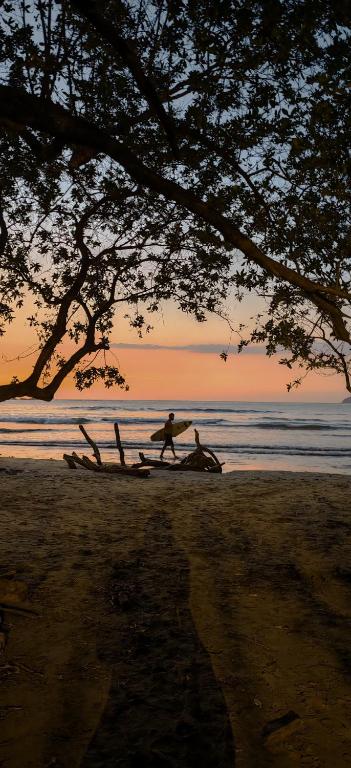 a couple of people on a beach with a surfboard at Pipas Apartment I Walk to the beach in Tamarindo