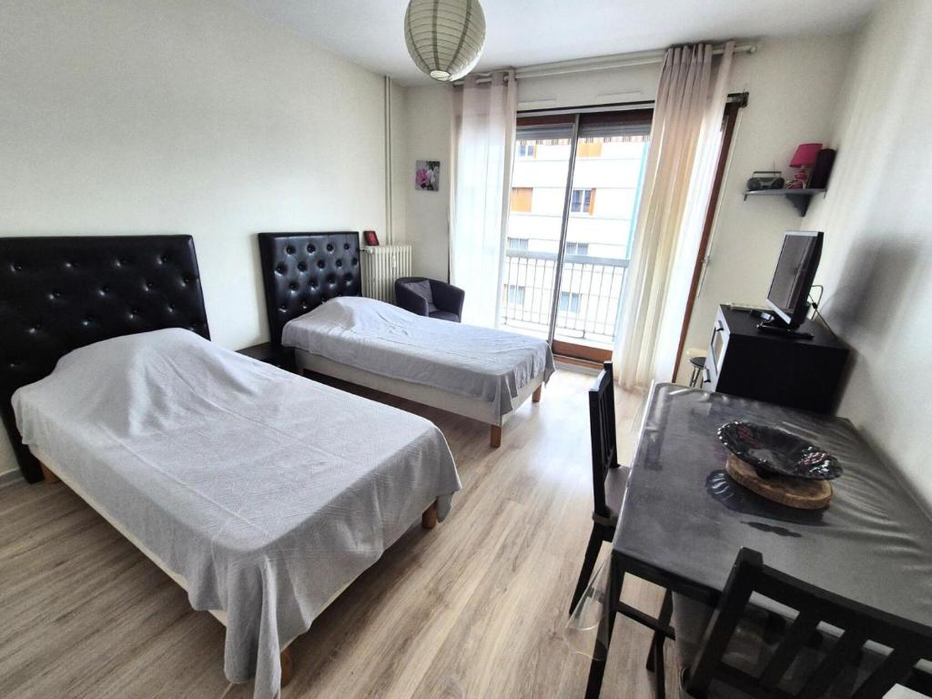 Cette chambre comprend deux lits et une table avec une table. dans l'établissement Residence Victoria - Studio dans quartier calme ! MAE-7004, à Aix-les-Bains