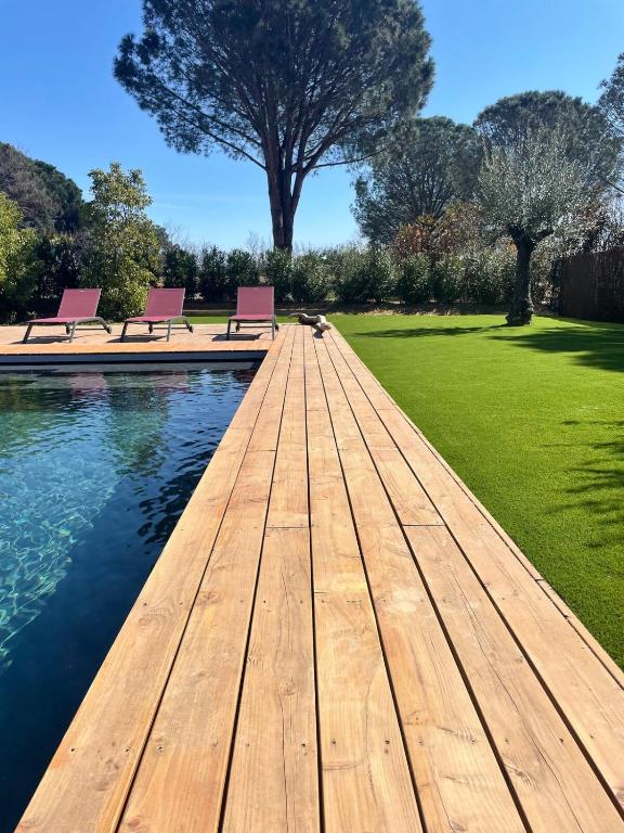 une promenade en bois menant à deux bancs dans un parc dans l'établissement Villa les Camphriers, à Grimaud