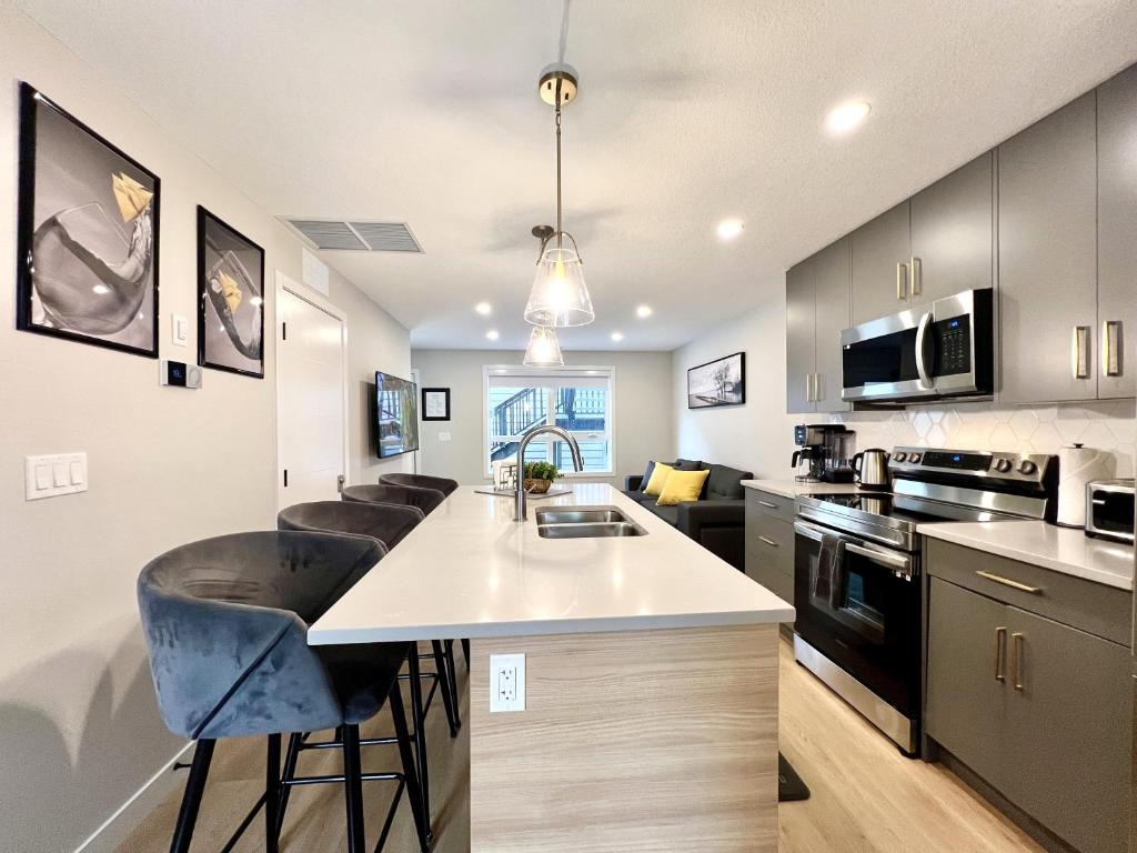 a kitchen with a counter and a kitchen island with bar stools at Brand New 2BR Condo with Outdoor Swimming Pool and Hot Tub in Canmore