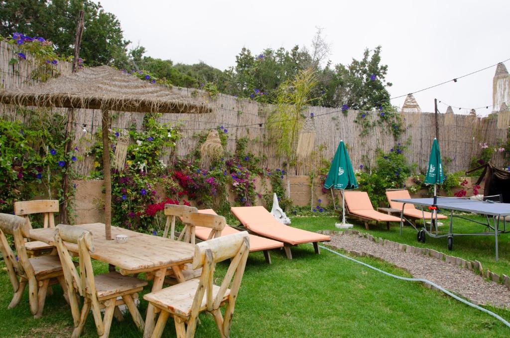 a garden with tables and chairs and umbrellas at harmony surf lodge in Taghazout