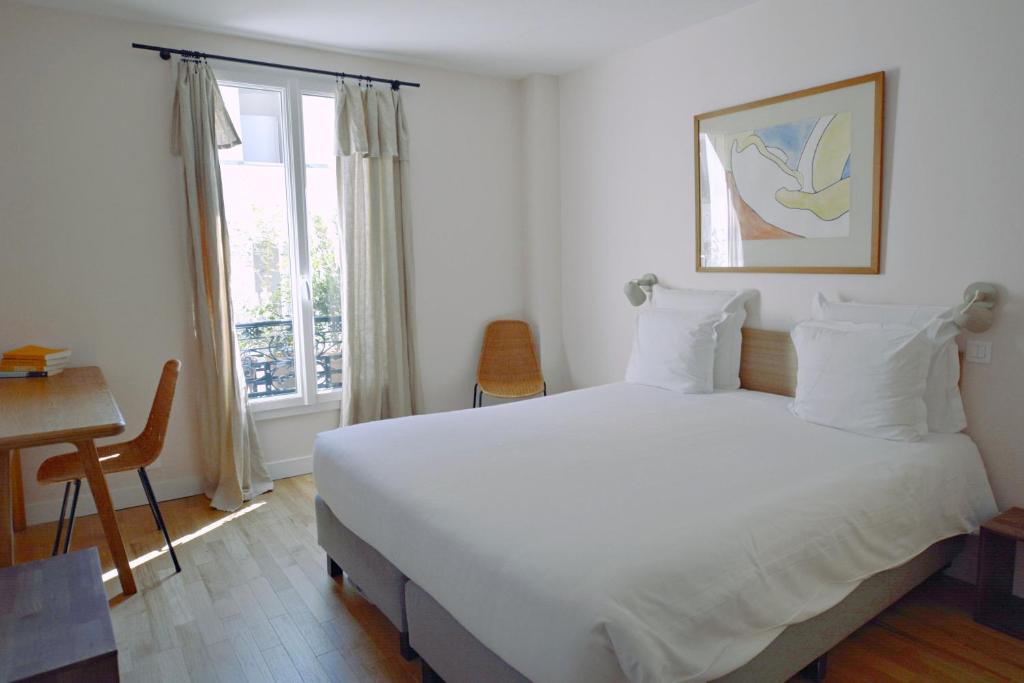 une chambre avec un grand lit blanc et une fenêtre dans l'établissement Hôtel Lucien, à Paris