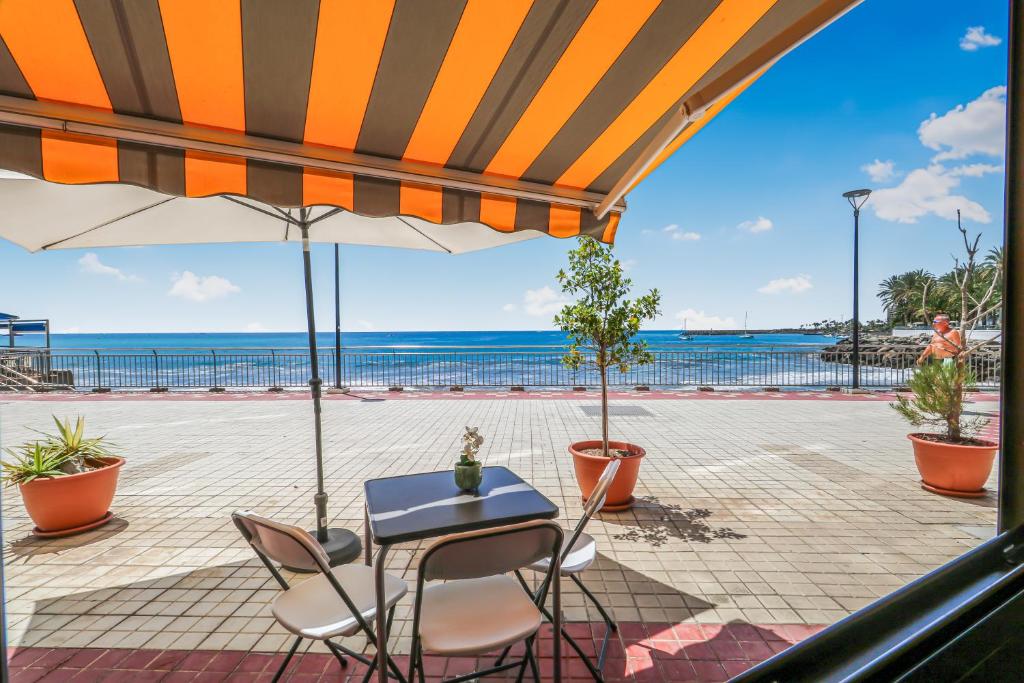 a patio with a table and chairs under an umbrella at Endless Seaview Patalavaca in Patalavaca