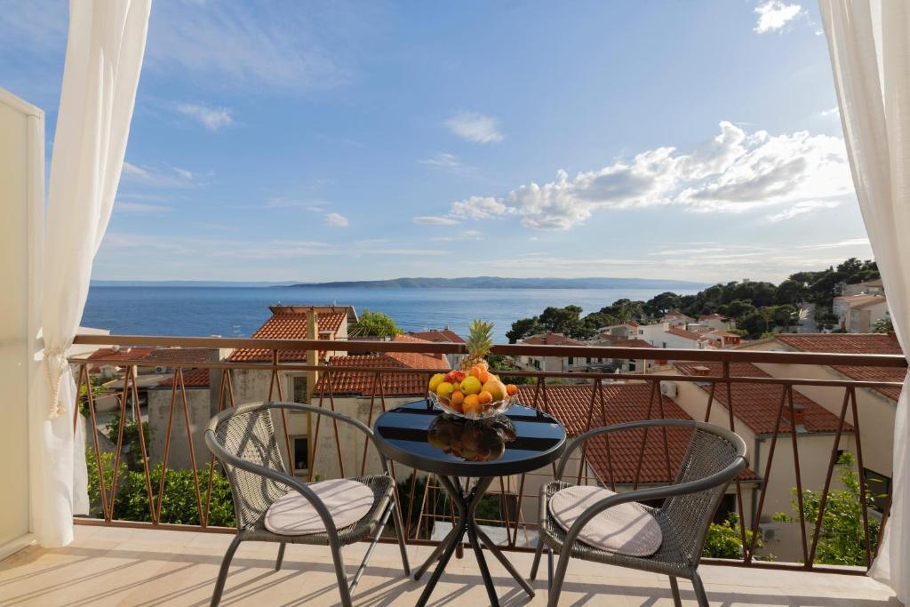 a table with a bowl of fruit on a balcony at Apartments Niki in Brela