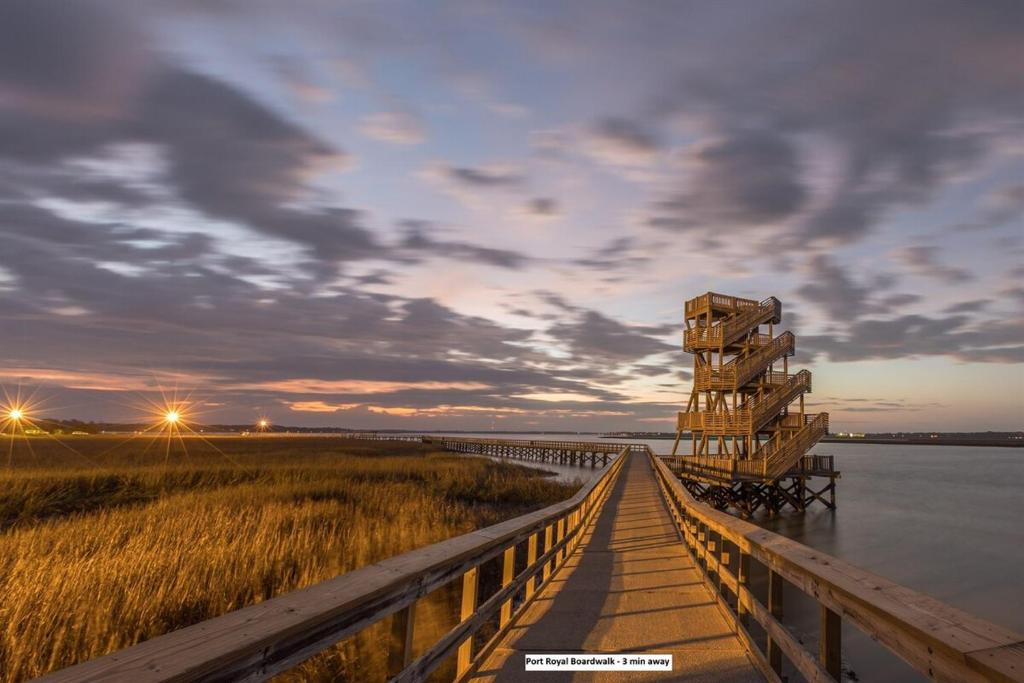 ein Holzsteg, der bei Sonnenuntergang ins Wasser führt in der Unterkunft Gritz & Giggles, Where Southern Charm Meets Belly Laughs in Port Royal
