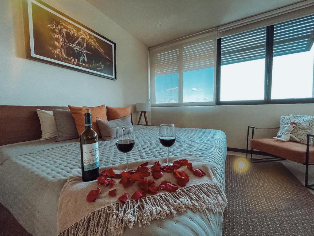 a bedroom with a bed with two glasses of wine at Sunrise 2BR Apt Steps from the Beach with Pool View in Holbox Island