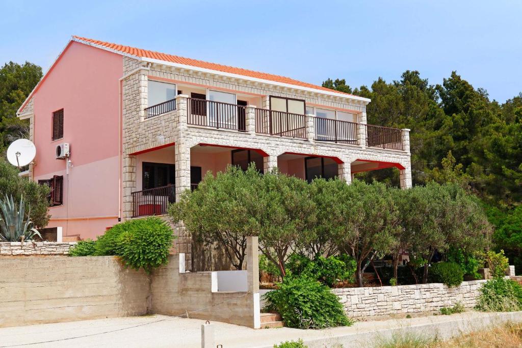 a pink house with trees in front of it at Apartments Doro in Vela Luka