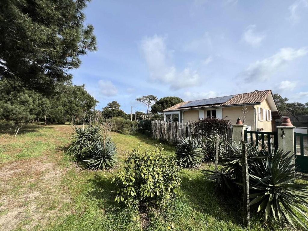une maison avec une clôture et des plantes dans une cour dans l'établissement Résidence 058-vendays Montalivet - 058 - Petit coin paisible à côté des pins et à 200m de l'Océan MAE-4871, à Vendays-Montalivet