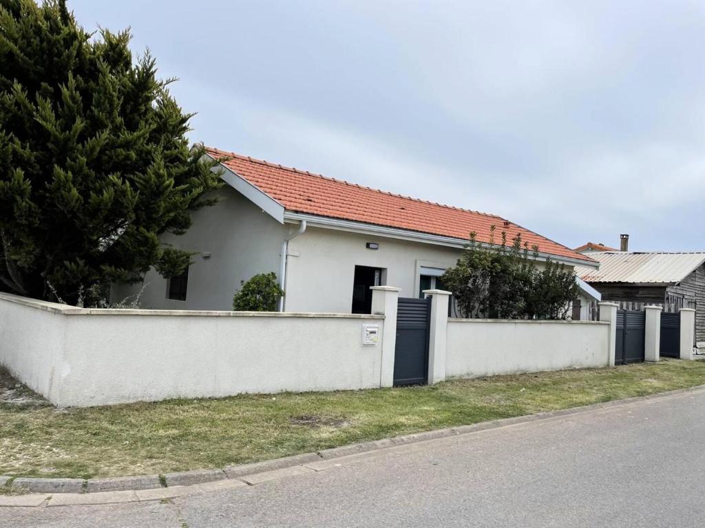 une maison blanche avec une clôture à côté d'une rue dans l'établissement Résidence 112-montalivet - 112 - Jolie maison en plein cœur de la station balnéaire de Montalivet MAE-7111, à Vendays-Montalivet
