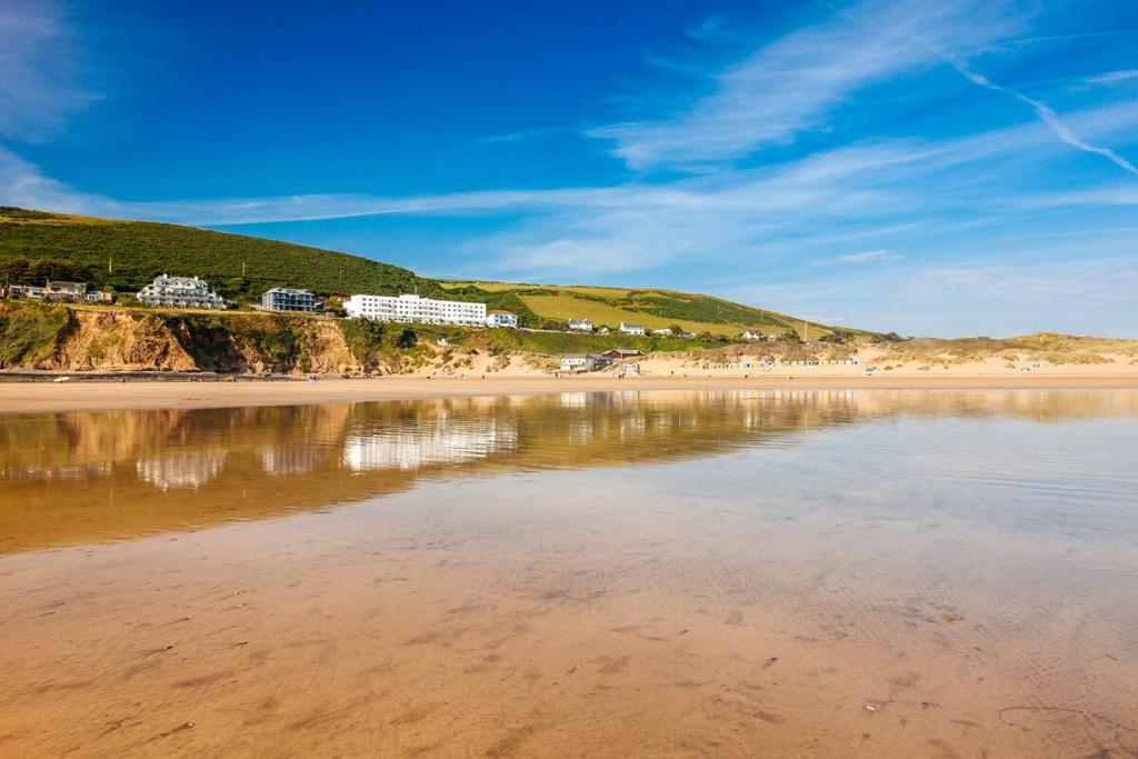 Blick auf einen Strand mit Gebäuden im Hintergrund in der Unterkunft Cosy North Devon Thatched Cottage near beaches in Marwood