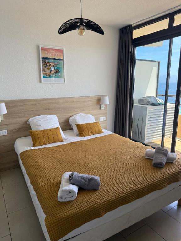 une chambre avec un grand lit avec des serviettes dessus dans l'établissement Beau Studio vue sur mer, route des sanguinaires, à Ajaccio