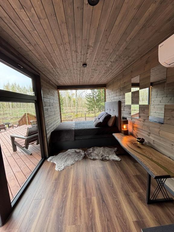 Una habitación con una cama y una pared de madera. en Sidrabgrava - Luxury cabin in woods, en Limbaži