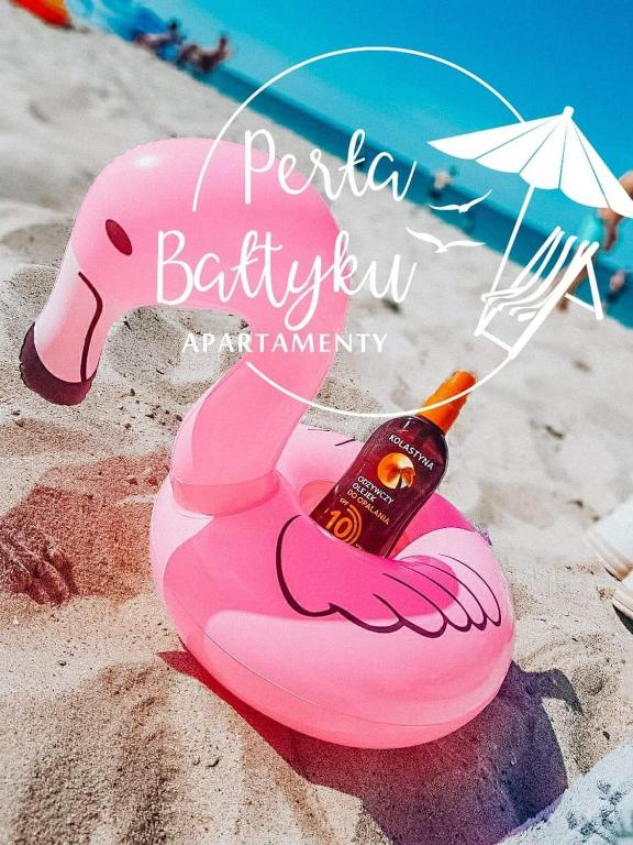 a pink flamingo toy on the beach with an umbrella at Apartamenty Perła Bałtyku in Władysławowo