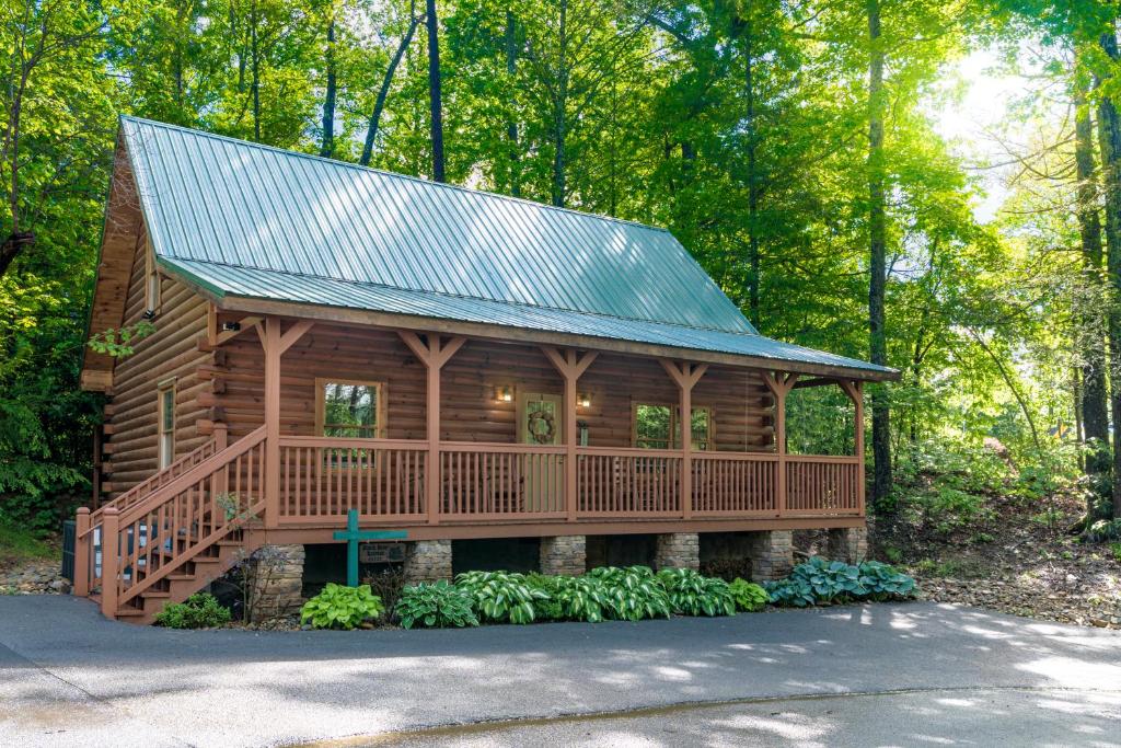 eine Blockhütte im Wald mit einem Metalldach in der Unterkunft Gorgeous 32in GatlinburgwFree Tickets to Dollywood,Anakeesta,AquariumClose2RockyTopSportsWorld in Gatlinburg