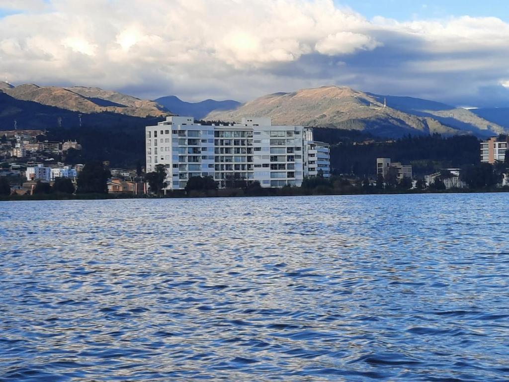 un gran edificio blanco en la orilla de un cuerpo de agua en Hermoso Apartamento con Vista al Lago, en Paipa