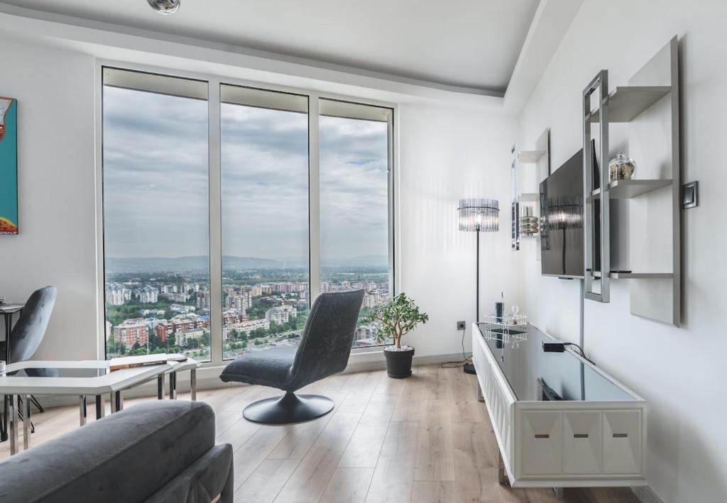 a living room with a couch and a table and windows at Stylish 28F Gym Free Pkg Secured in Skopje