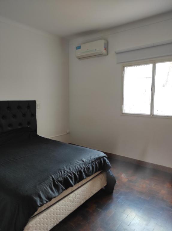 a bedroom with a black bed and a window at Depto Centrico en Planta Alta in Bahía Blanca
