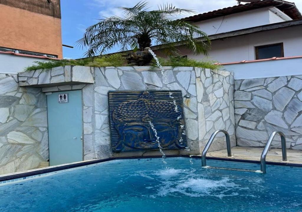 a swimming pool with a water fountain at Chales Camburi in Camburi