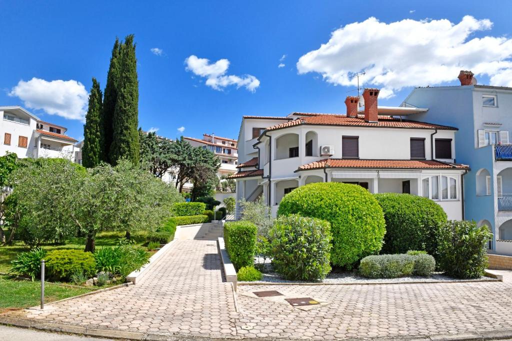 a large white house with bushes and trees at Apartments Gloria in Vrsar