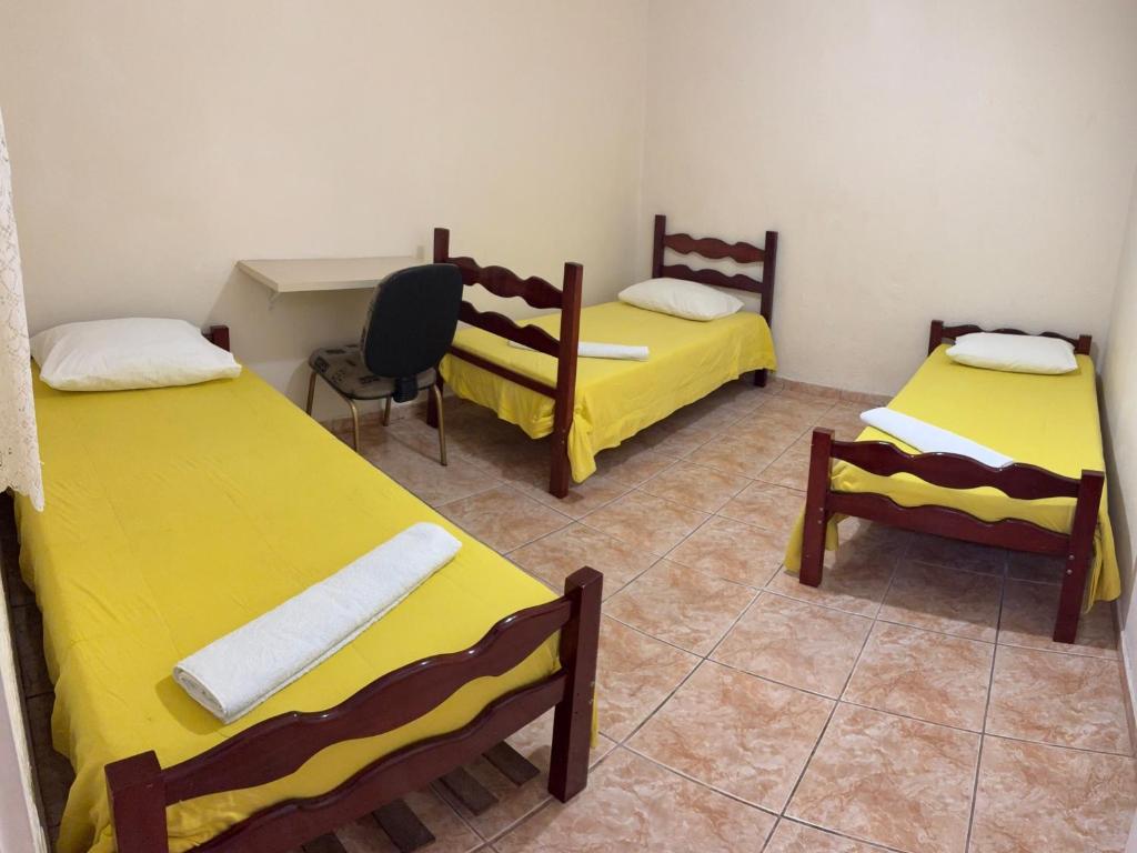 a room with three beds and a desk and a chair at POUSADA NOVA BARãO in Campinas