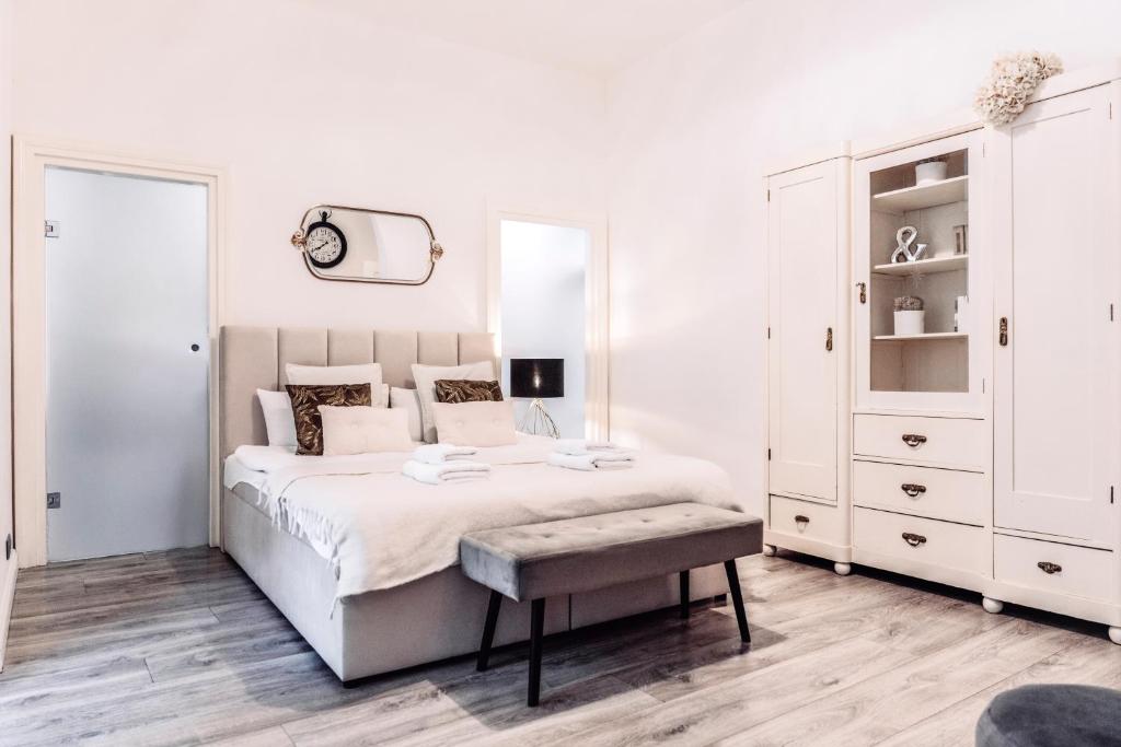 biała sypialnia z dużym łóżkiem i ławką w obiekcie Wenceslas Square / Main Station - NEW STUDIO***** w Pradze