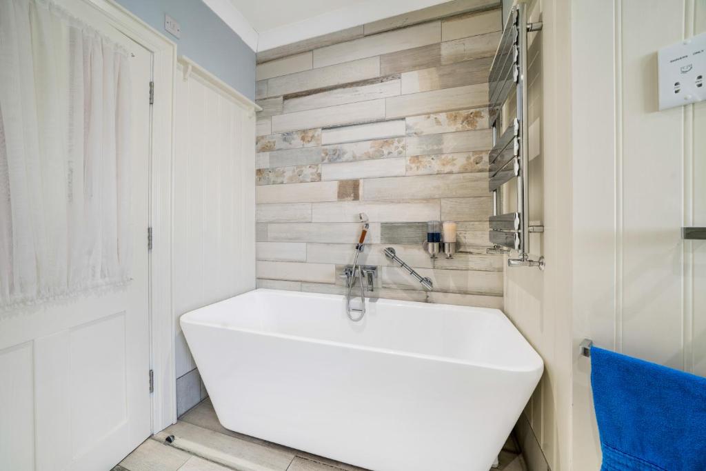 a bathroom with a white tub and wooden wall at Anvershiel House in Portrush