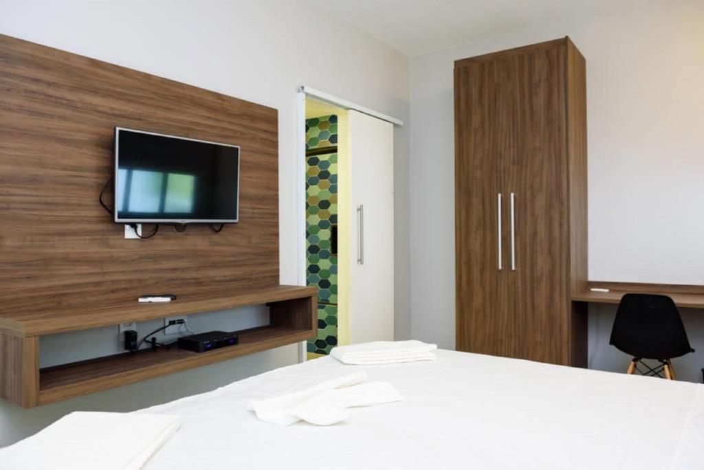 a bedroom with a bed with a tv on the wall at Icaraí Suítes in Niterói
