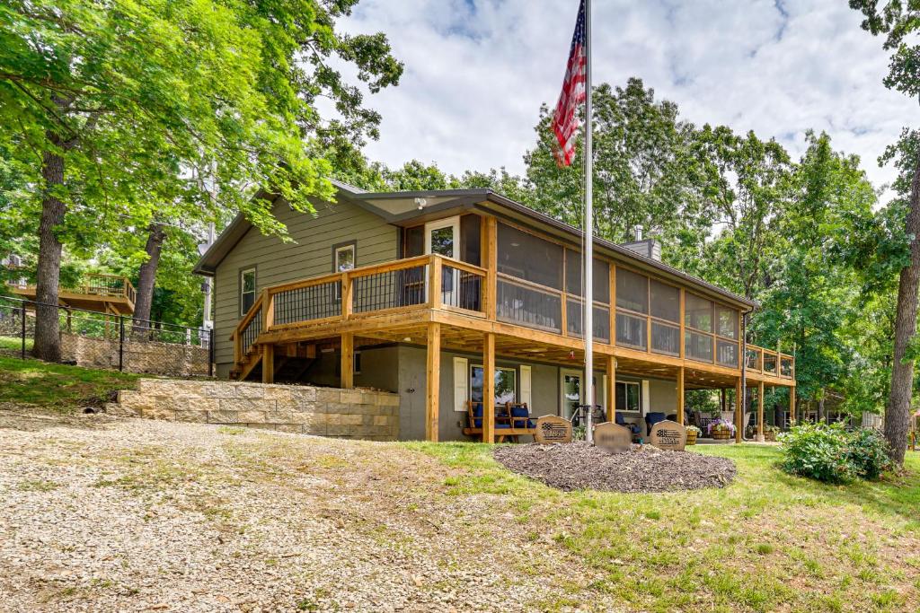a large wooden house with a flag in front of it at Truman Lake Retreat Large Deck and On-Site Fishing! in Clinton