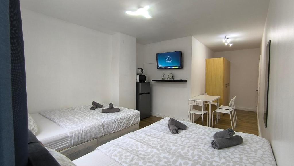 4 pers studio style room Near South Wimledon station R3 في لندن: غرفة فندقية بسريرين وطاولة مع طاولة