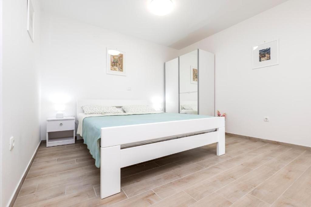 a white bedroom with a bed and a mirror at Apartments by the sea Veli Losinj, Losinj - 24542 in Veli Lošinj