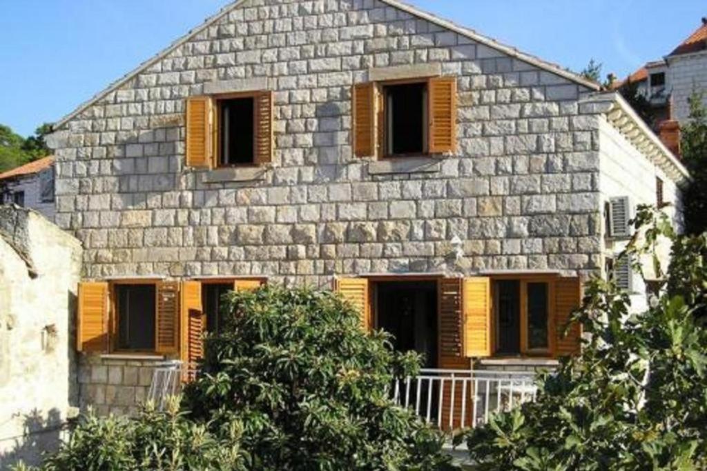- un bâtiment en pierre avec des volets en bois dans l'établissement Apartments by the sea Cavtat, Dubrovnik - 24545, à Cavtat