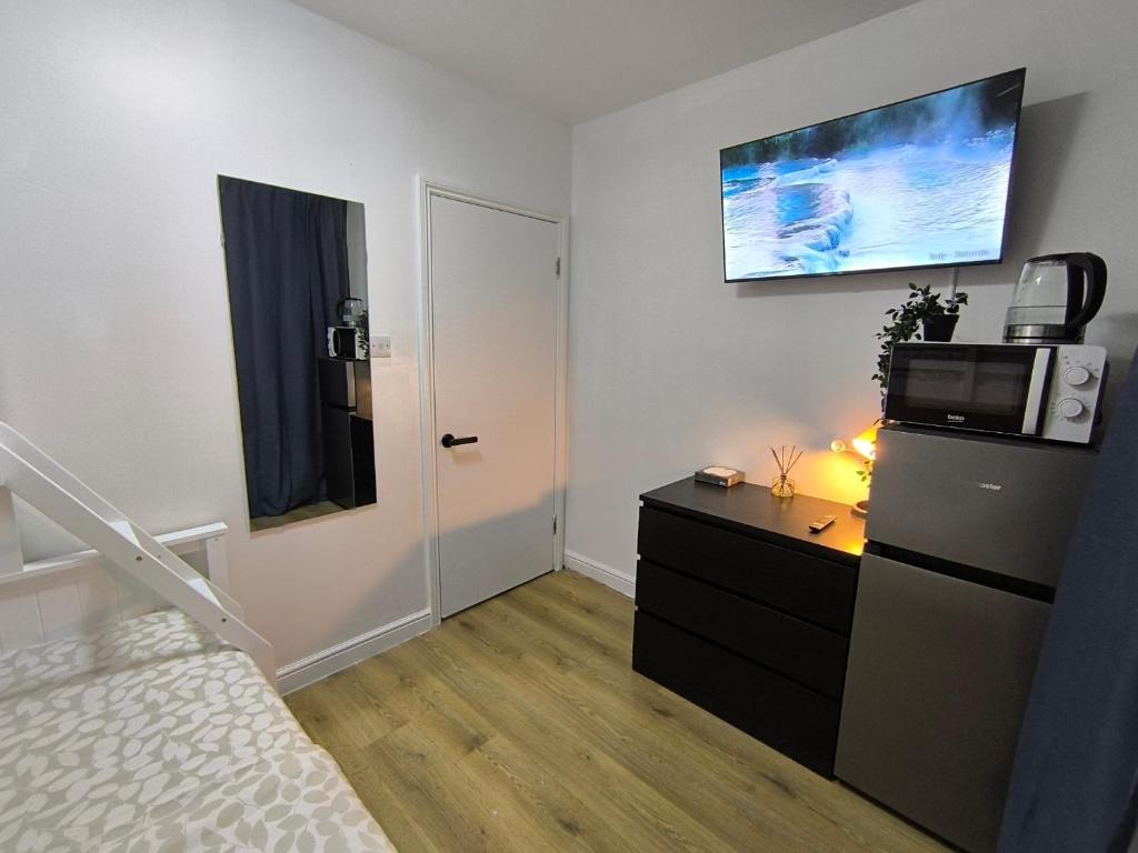 a bedroom with a bed and a microwave and a refrigerator at 3 Persons Room, 1min walk from South Wimbledon Station in London