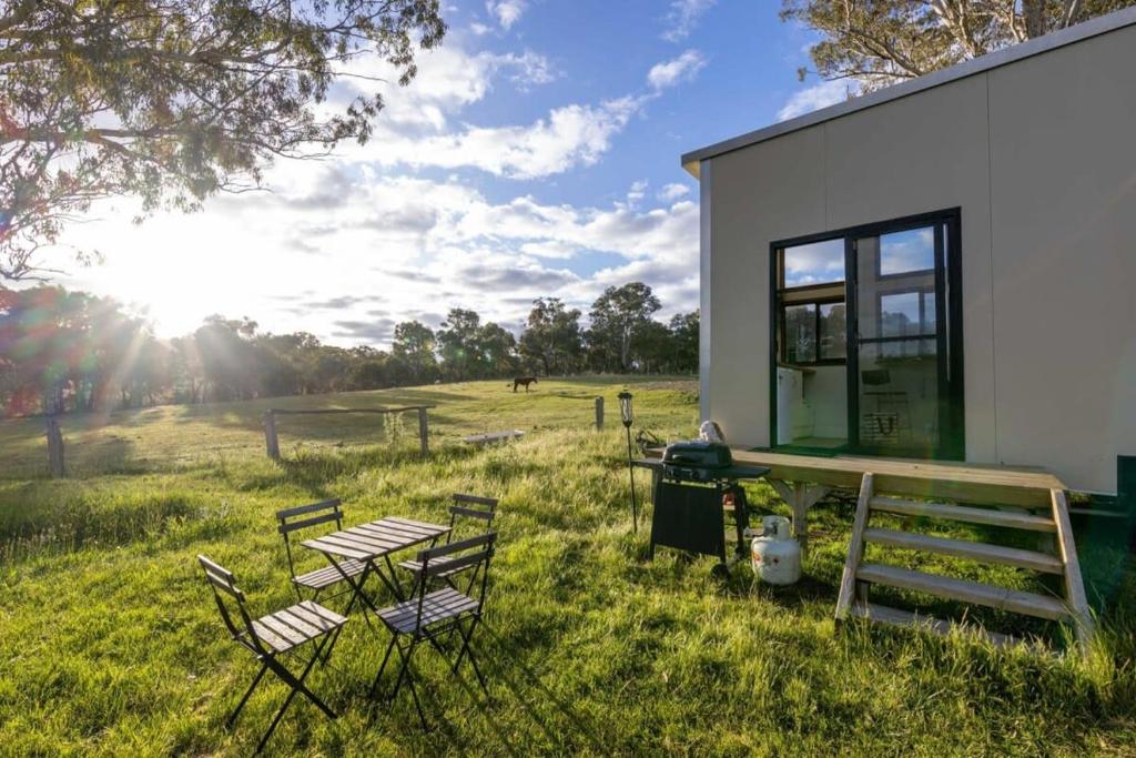 un gruppo di sedie e un tavolo in un campo di Sithuri Tiny House by Tiny Away a Windeyer