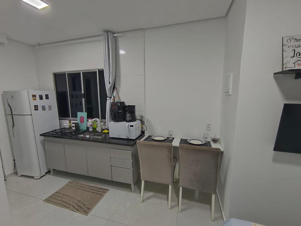 a kitchen with a refrigerator and a table and chairs at Studio CG 4, Campo Grande RJ in Estação Inhoaíba