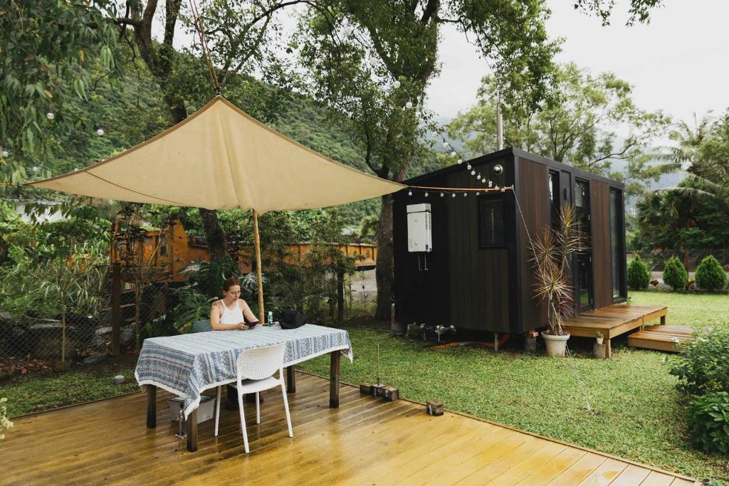 eine Frau, die an einem Tisch in einem Hinterhof mit einem Zelt sitzt in der Unterkunft Mountain Silhouette Cottage 2 by Tiny Away in Jingmei