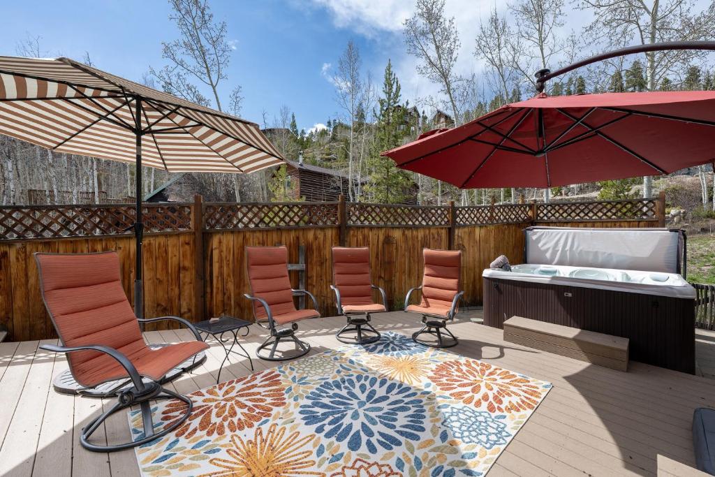 a patio with chairs and umbrellas on a deck at West Portal Cabin cabin in Grand Lake