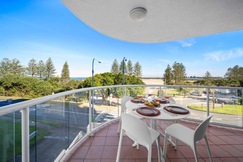 a balcony with a table and chairs and a view of a street at Caprina in Caloundra in Caloundra