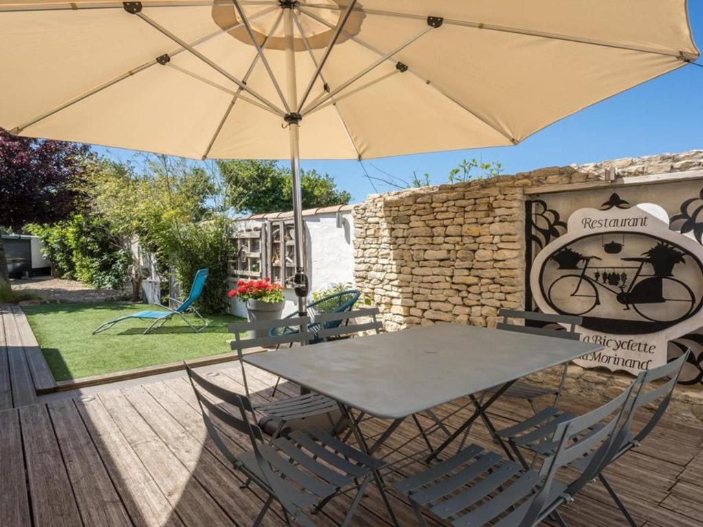 une table et des chaises avec un parasol sur une terrasse dans l'établissement Maison charmante avec WiFi près des plages et pistes cyclables - FR-1-835-9, au Bois-Plage-en-Ré