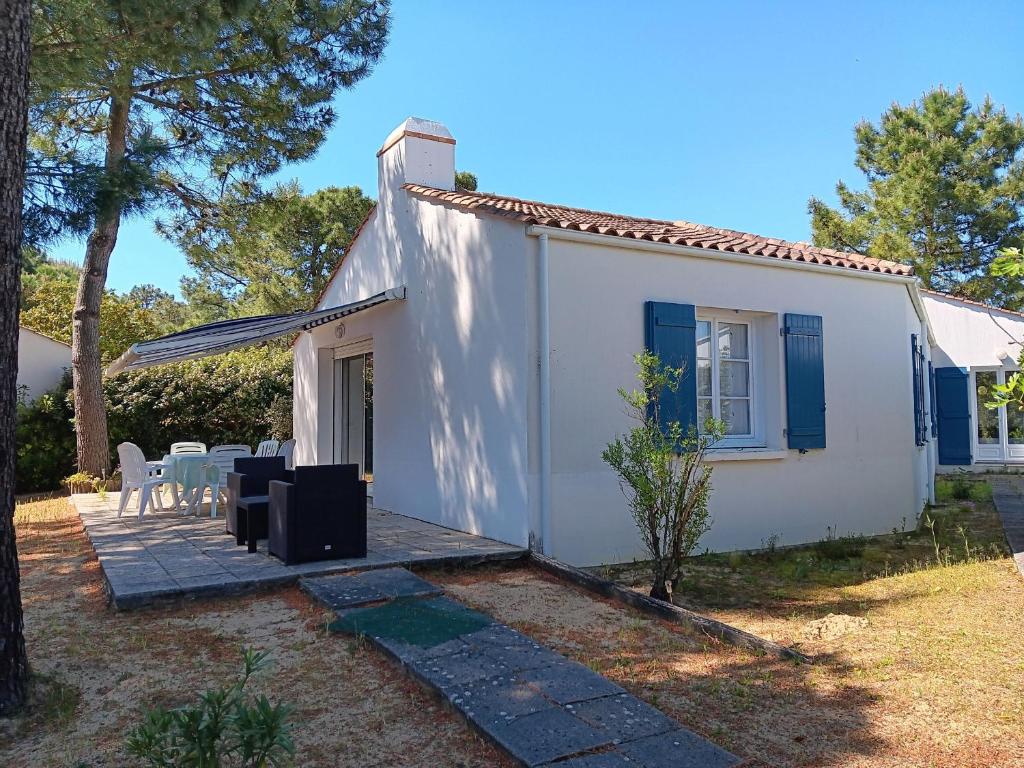 Cette petite maison blanche dispose d'une terrasse et de chaises. dans l'établissement Maisonnette confort 7 pers, accès plage direct - FR-1-476-237, à La Faute-sur-Mer