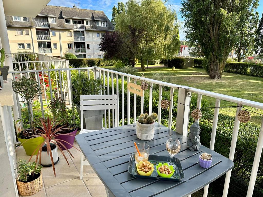 une table bleue avec un plateau de nourriture sur un balcon dans l'établissement Charmant 2 pièces, balcon, proche centre-ville Cabourg, 4 pers, parking sécurisé - FR-1-487-360, à Cabourg