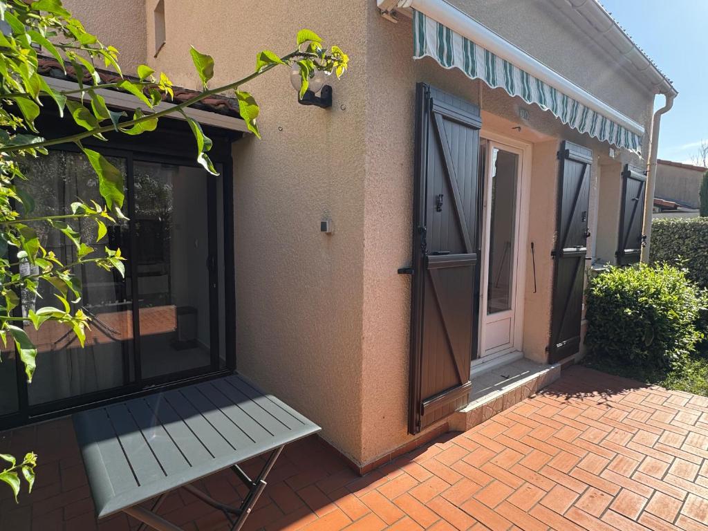 un porche avec un banc blanc à côté d'une porte dans l'établissement Maison plain-pied à Argelès-sur-Mer avec garage, proche transports et commerces - FR-1-732-87, à Argelès-sur-Mer