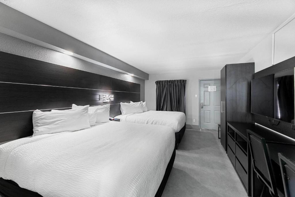 a hotel room with two beds and a flat screen tv at Baymont by Wyndham San Antonio Near Lackland AFB in San Antonio
