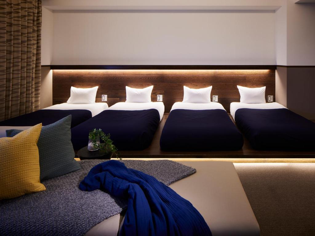 une chambre avec trois lits et une couverture bleue dans l'établissement Minn Asakusa, à Tokyo