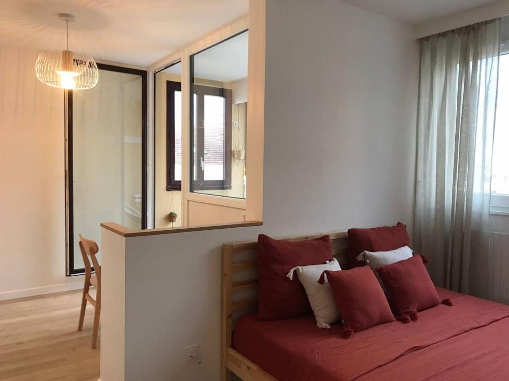 - une chambre dotée d'un lit avec des draps rouges et un miroir dans l'établissement Le Studio Lumière - Balcony - 5min Part-Dieu, à Lyon