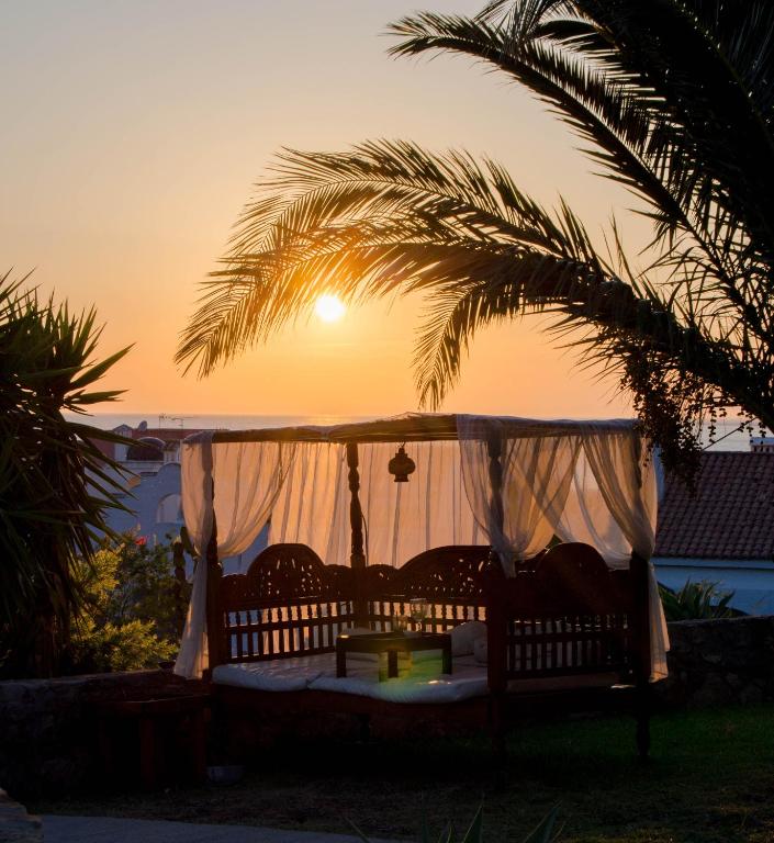 a swing in front of a palm tree with the sunset at El Cortijo de Zahara by QHotels in Zahara de los Atunes