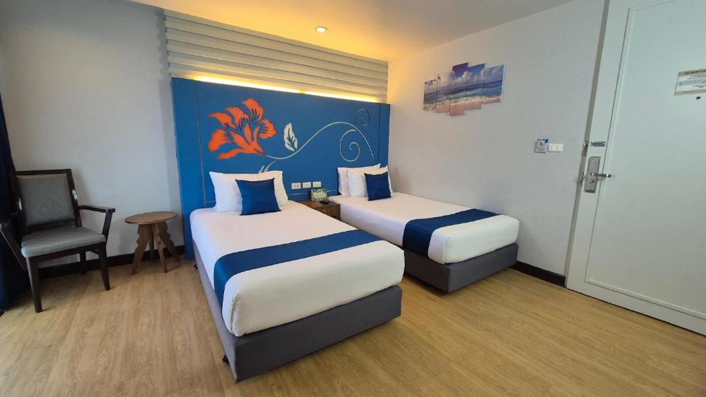 a hotel room with two beds and a chair at Days Inn by Wyndham Patong Beach in Patong Beach
