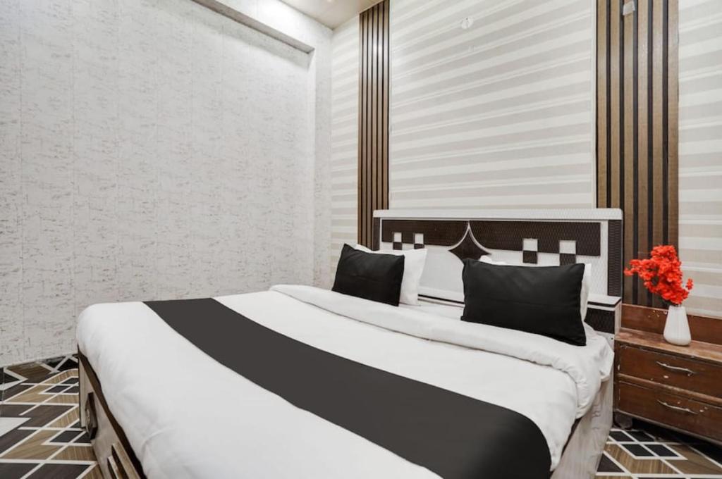 a bedroom with a large white bed with black pillows at EMERGE HOTEl in Hardoī