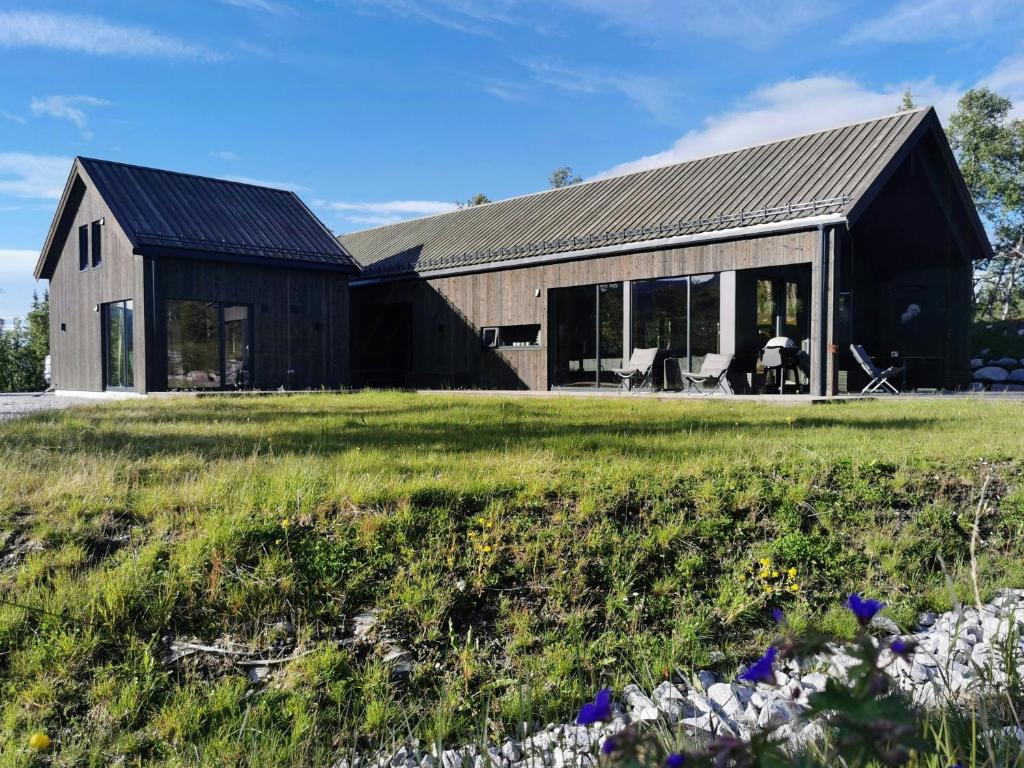a barn with a black roof and a green field at Family Cabin With Annexe In Haglebu in Eggedal