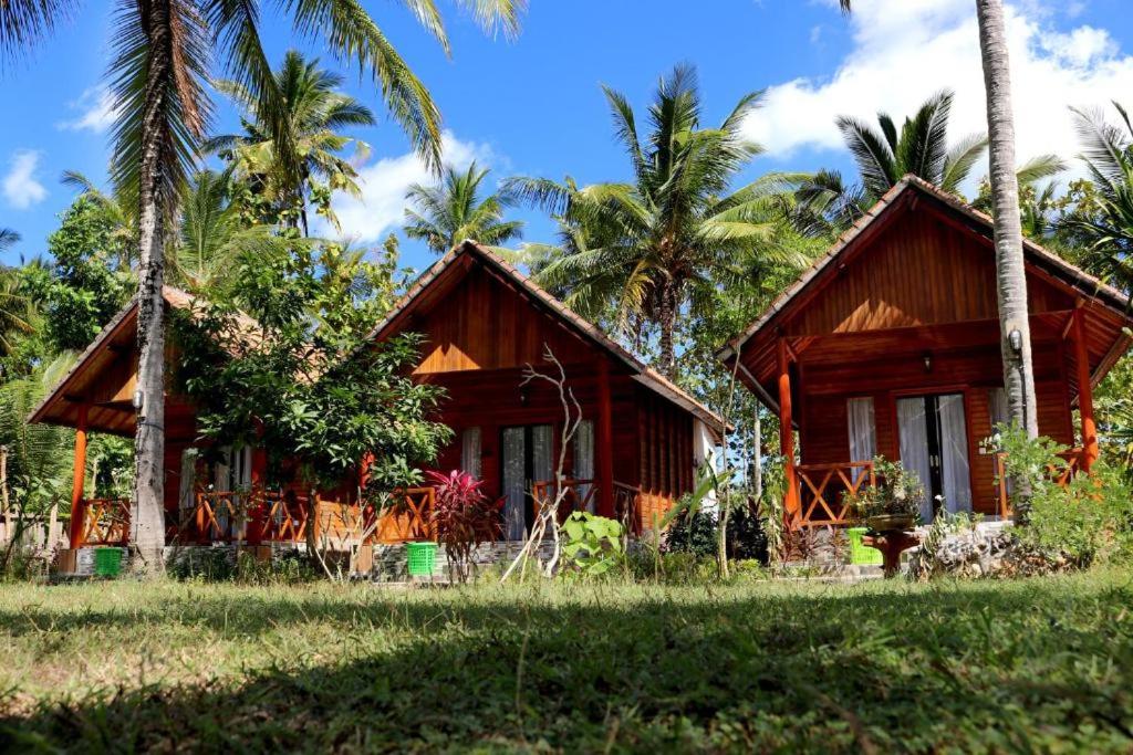 a wooden house with palm trees in front of it at Dangin Kubu Pedoman in Toyapakeh