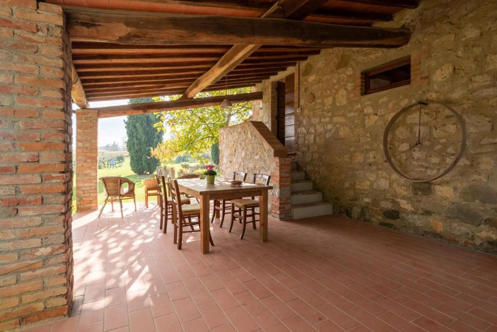 Un patio con una mesa y sillas y una pared de ladrillos. en Villa In The Farmhouse With Pool In Tuscany, en Bucine